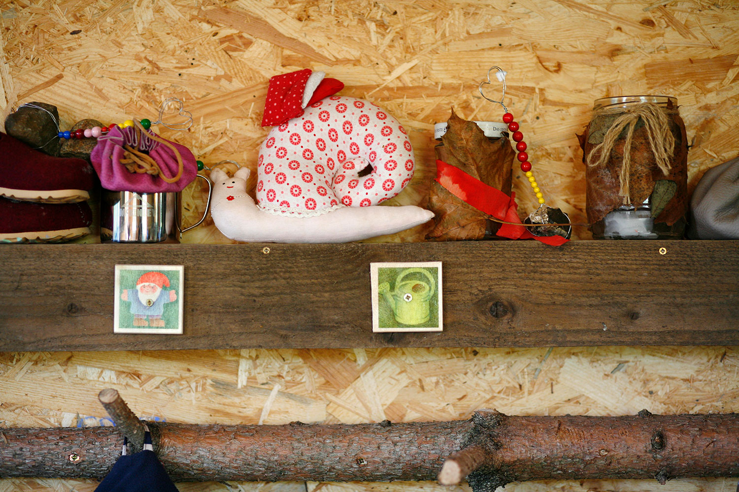 Naturkita Waldforscher - Auf einem Holzregal in der Schutzhütte stehen Bastelarbeiten und Kuscheltiere der Kinder.