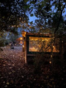 Naturkita im Zentrum von Hamburg - Kerzenlicht und Lichterketten beleuchten eine Schutzhütte in einer Waldforscher Naturkita in der Herbstdämmerung.