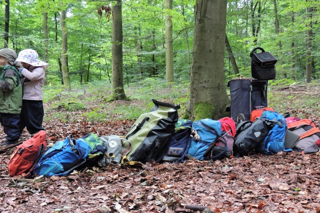 Waldforscher Naturkita - In einer Reihe liegen die Kinderrucksäcke im Wald, für einen Rucksackausflug